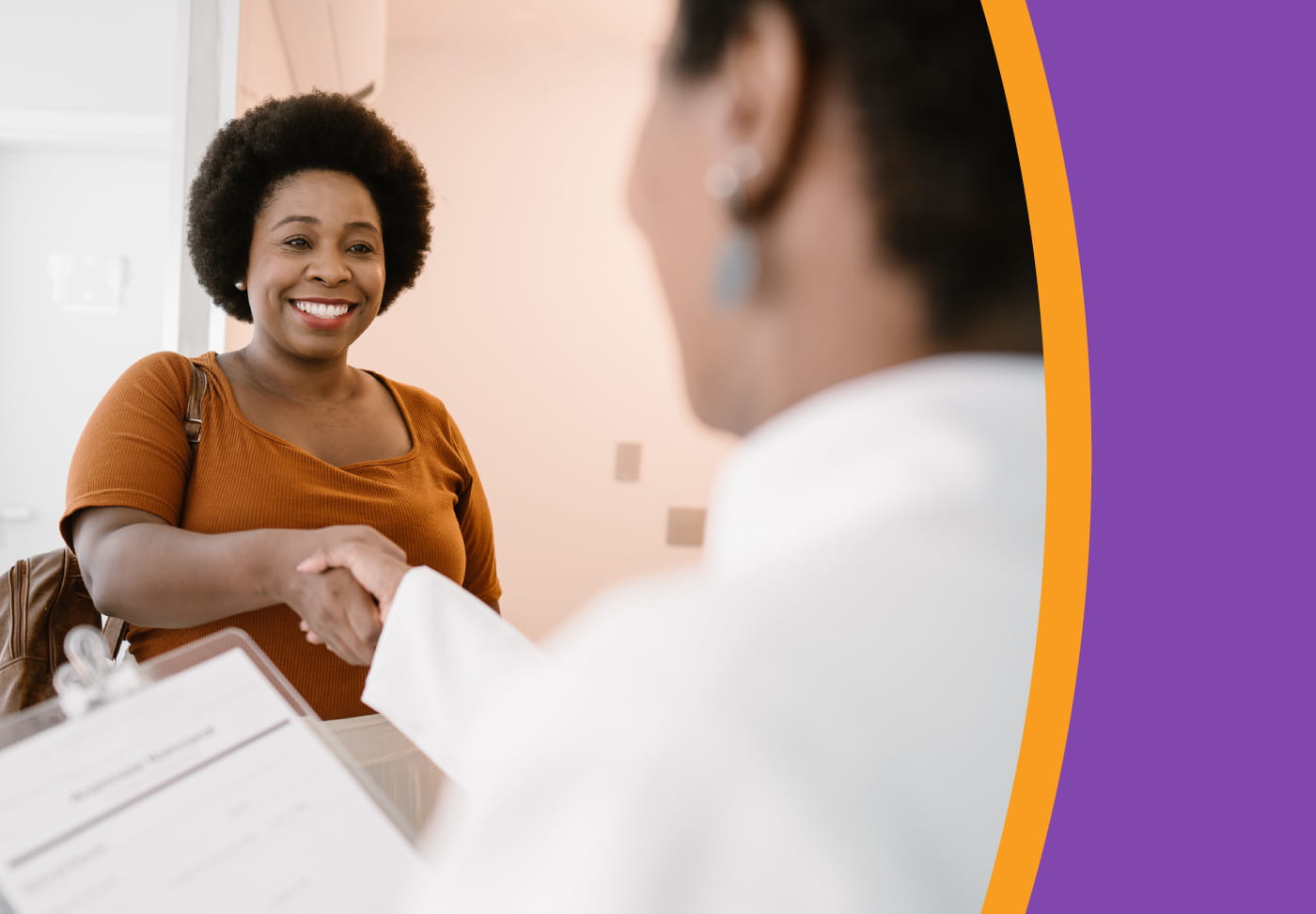A smiling patient shakes hands with her healthcare provider.
